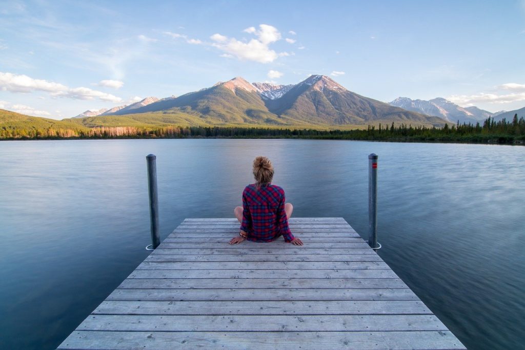 Person sitzend auf Steg am See